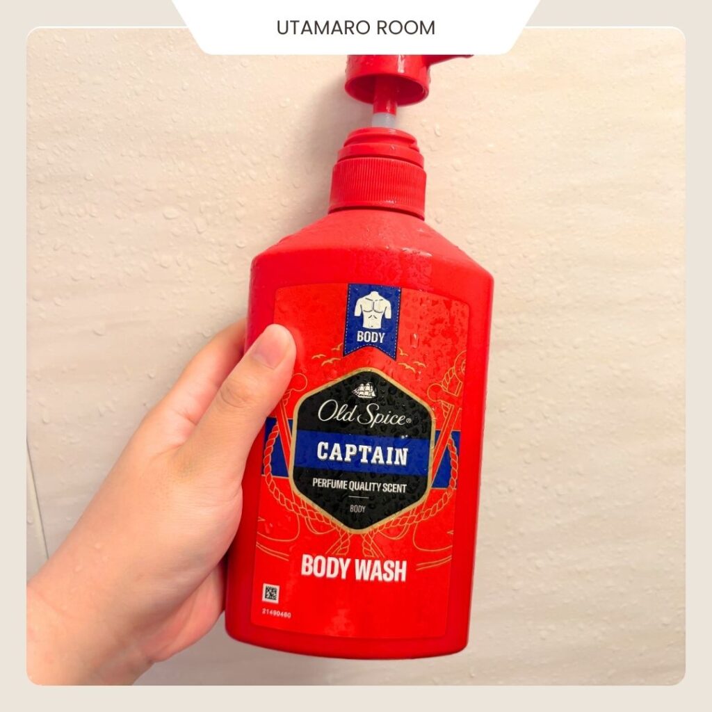 オールドスパイス キャプテン ベルガモットのボディウォッシュのボトルを浴室で手に持ったところ。赤いポンプ式の容器